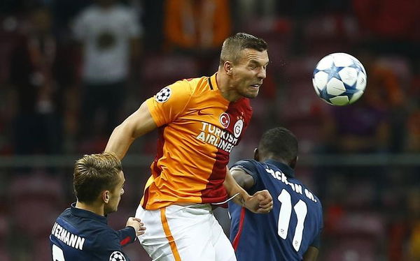 Galatasaray&#8217;s Podolski jumps for the ball past Atletico Madrid&#8217;s Griezmann and Martinez during their Champions League Group C soccer match in Istanbul