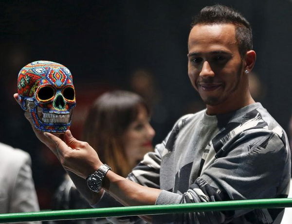 Mercedes Formula One driver Lewis Hamilton of Britain holds up at a traditional Day of the Dead Mexican skull at the Coliseo Arena during a promotional event in Mexico City