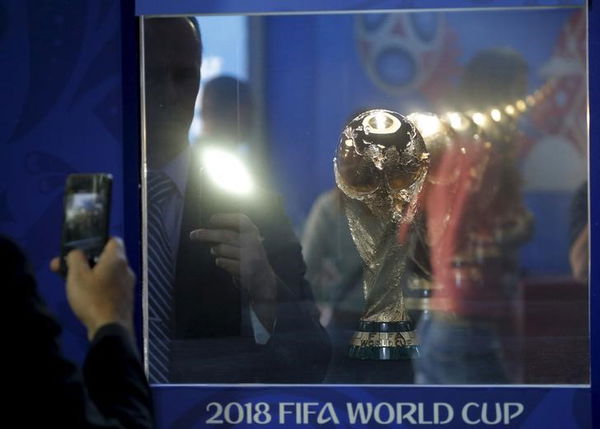 A man takes pictures of the World Cup trophy, which is on display during a ceremony marking 1,000 days until the beginning of the 2018 FIFA World Cup in Moscow