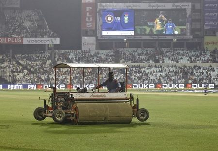 A groundsman works to dry the outfield after the rain delayed the third and final Twenty20 cricket match between India and South Africa in Kolkata