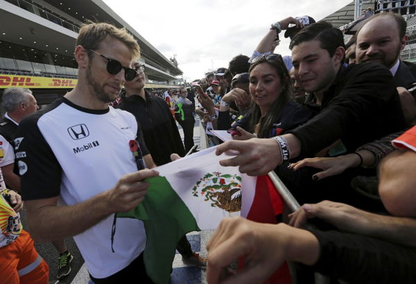 McLaren Formula One driver Jenson Button of Britain autographs a Mexican flag for a fan before the Mexican F1 Grand Prix at Autodromo Hermanos Rodriguez