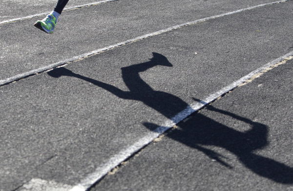 A sportsman casts a shadow on a race track while training at a local stadium in Stavropol