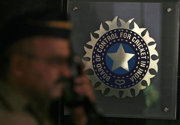 A policeman walks past logo of BCCI in Mumbai