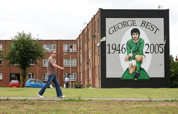 A man walks near a George Best mural in the Gregagh Estate, Belfast