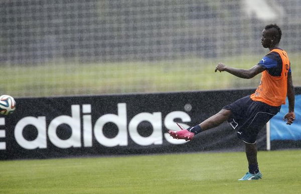 Italy&#8217;s national soccer player Balotelli kicks the ball as an Adidas advertising banner is seen during a training session ahead of the 2014 World Cup in Mangaratiba