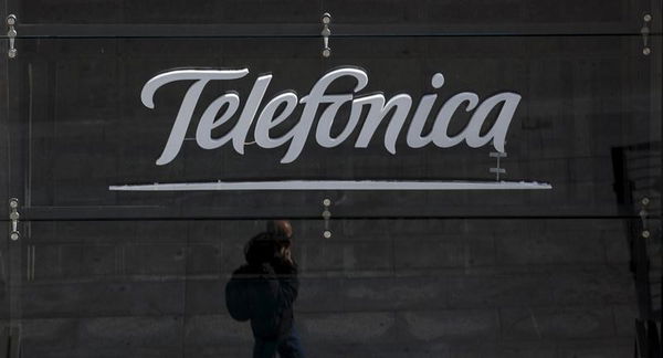 A reflection of a man talking on his phone is seen outside Telefonica&#8217;s flagship store in central Madrid