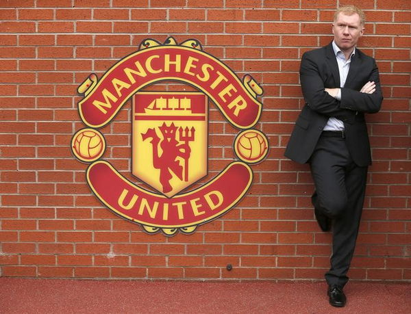 Former Manchester United player Scholes stands next to a team emblem before their English Premier League soccer match against Everton at Old Trafford in Manchester