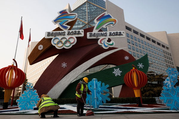 Workers clean up in front of a display of the logos of the Beijing 2022 Winter Olympics and Paralympics in Beijing