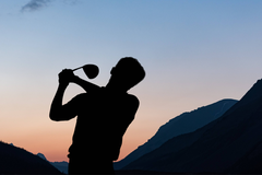 Composition of silhouette of male golf player over landscape and blue sky with copy space. sport and competition concept