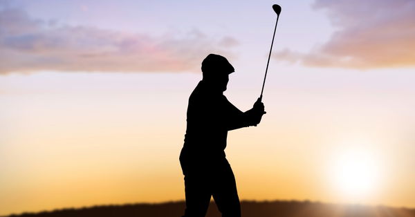 Composition of silhouette of male golf player over landscape and sun setting with copy space Composi