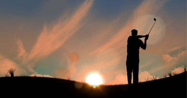 Composition of silhouette of male golf player over landscape and sun setting with copy space Composi