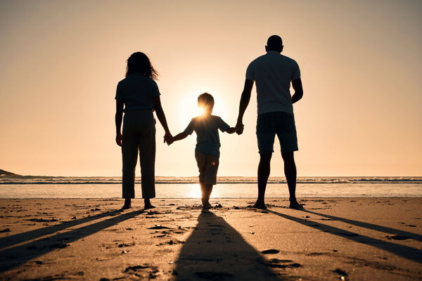 Family silhouette at the beach, holding hands at sunset and people with love, care and support outdoor. Mom, dad and kid