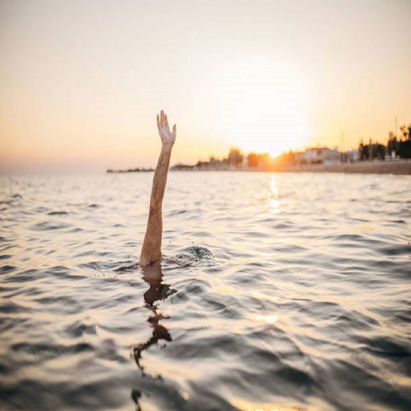 A man is drowning, asking for help with his hand