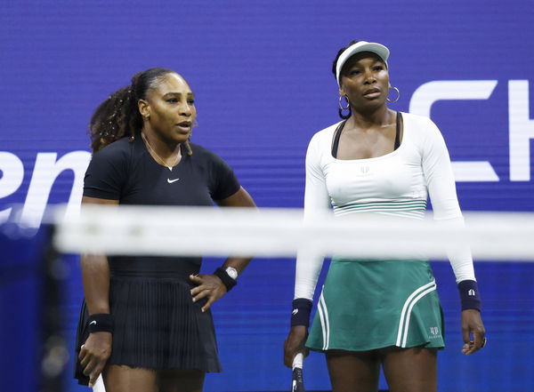 Serena Williams and Venus Williams talk between points in their first round doubles match against Lucie Hradecka of the