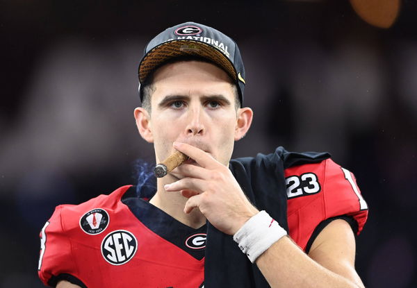 Stetson Bennett 13 of the Georgia Bulldogs celebrates with teammates and a cigar after defeating the TCU Horned Frogs at