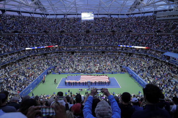 The United States flay is unfurled at center court in ceremonies before Roger Federer of Switzerland